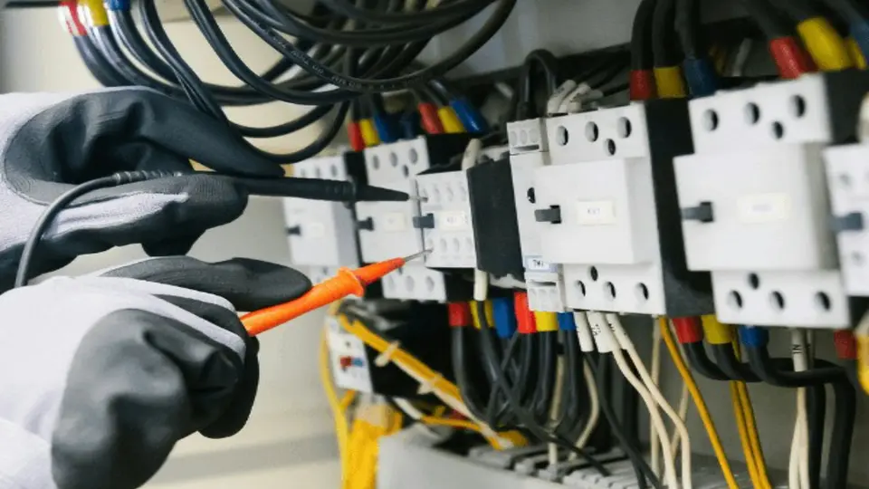 Medição elétrica em painel de controle durante verificação de campo